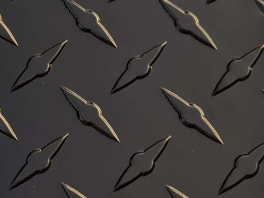 A large, black aluminum diamond plate sheet with a textured, raised pattern, backed with durable PVC material, measuring 49 inches by 96 inches.